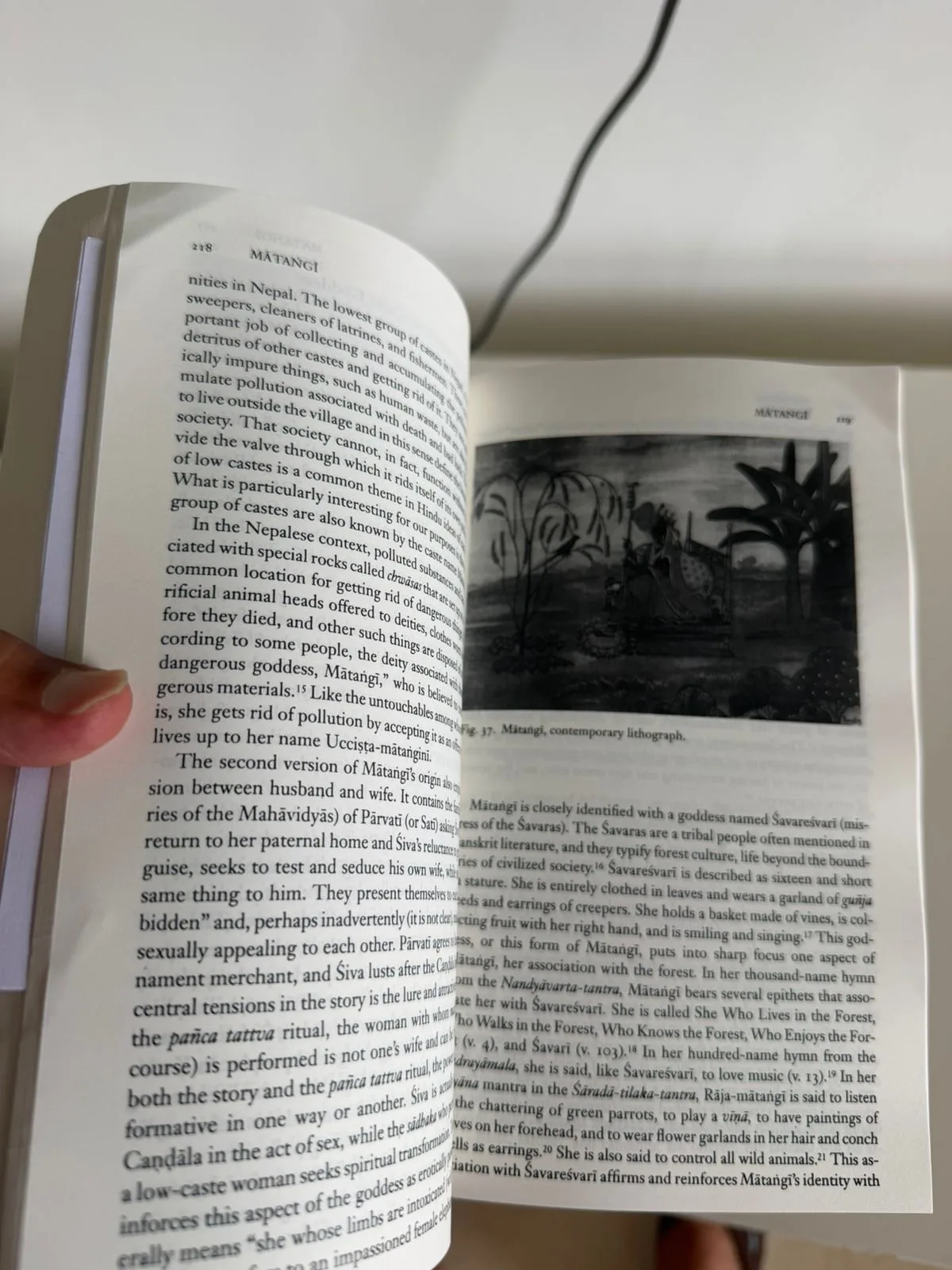 Open pages of the book showing a lithograph of the goddess Matangi in the forest